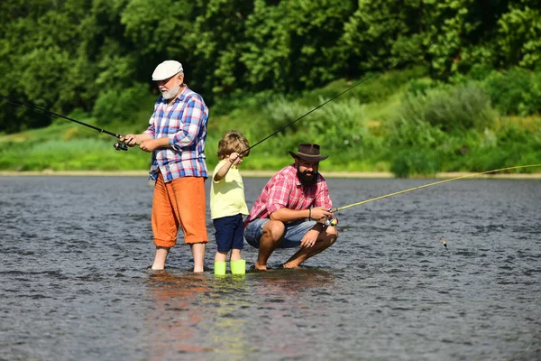 Nonno, padre e nipote pescano insieme. Pescatori familiari che pescano con mulinello . — Foto Stock