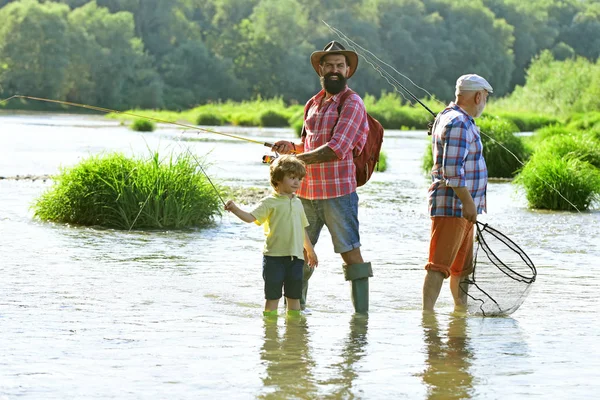 Papà e figlio pesca al lago. Padre e figlio pescano. Generazioni uomini. Ragazzo con padre e nonno pesca a mosca all'aperto su sfondo fiume . — Foto Stock