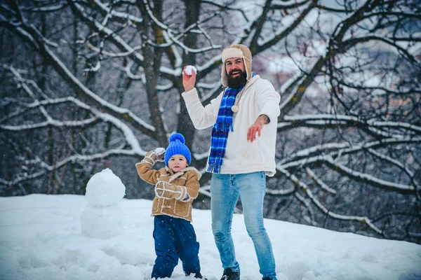 Padre y su hijo jugando al aire libre. Lindo niño y padre feliz en el campo cubierto de nieve al aire libre. Familia de invierno en el helado parque de invierno. Vacaciones de Navidad . — Foto de Stock