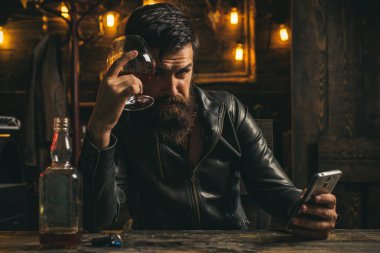 Şık adam sakal portresi. Vintage berber dükkanı, tıraş. Erkek güzelliği, moda. Erkek sakalı ve bıyığı. Adam düşünüyor. Elinde telefon var. Pub.