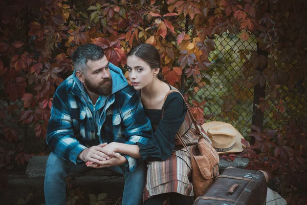 Young couple sitting outdoors at the park on beautiful autumn day. Lifestyle, happy couple of two play on a sunny day in the park. Girl and bearded guy or happy lovers hug on date. — Stock Photo, Image