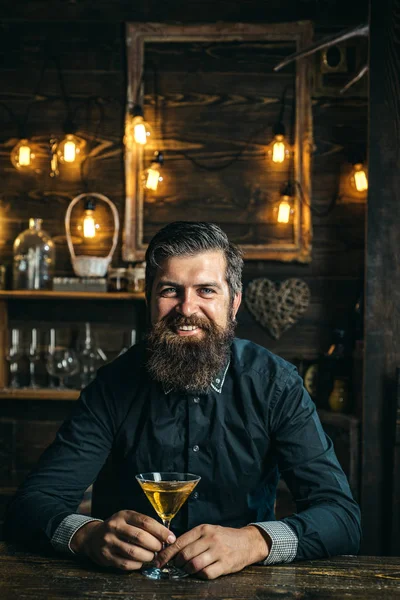 Man drinkt een cocktail. Barman hipster. Alcoholist met fles en glas drinken Martini 's nachts. — Stockfoto