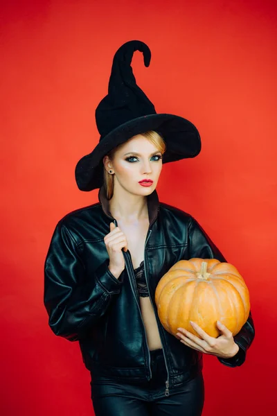 Emocjonalne młode kobiety w Halloweenowych kostiumach na imprezie na czerwonym tle z dynią. Koncepcja Halloween. — Zdjęcie stockowe