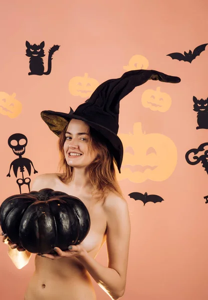 Kvinnan visar en vacker åsna eller rumpa. Kvinna med sexig röv poserar på pumpa. Sexig tjej har bästa idéer för Halloween. Naken kvinna häxa med Halloween hatt och pumpa. Nattfest bakgrund. — Stockfoto