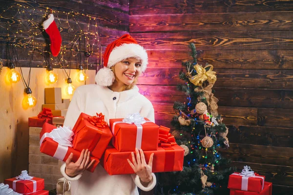 Noel Baba şapkası giymiş sarışın kadın model. Noel Baba şapkalı sevimli genç bir kadın. Coşku. Noel ağacı ile kapalı kız Moda portresi. Gülümseyen kadın evde Noel ağacı dekorasyon. — Stok fotoğraf