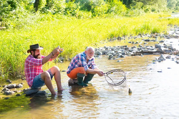 Padre con figlio sul fiume godendo pesca tenendo canne da pesca. Concetto di famiglia felice - padre e figlio insieme . — Foto Stock