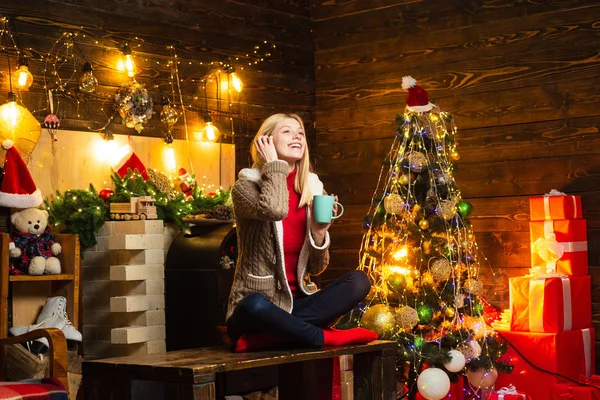 Plný radosti a lásky. Dívka si útulnou teplou atmosféru Štědrý večer. Příjemné chvíle. Vánoční radost. Žena dřevěný interiér vánoční ozdoby věnec světla. Vánoční stromek — Stock fotografie