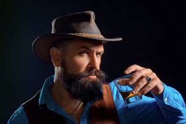 Takım elbiseli sakallı ve bıyıklı hipster, iş gününden sonra alkol içer. Neşeli sakallı adam pahalı viski içiyor.