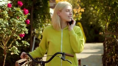 Mutlu kız telefonla poz. Yeşil gömlekli sarışın kadın seviniyor ve elinde cep telefonu tutuyor.