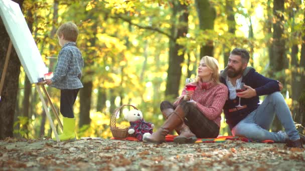 Gelukkige kind kunstenaar tekening foto op herfst natuur. Familie ouderschap en mensen concept-gelukkige moeder vader en kleine jongen in herfst Park. Familie spelen in herfst Park en plezier hebben. — Stockvideo