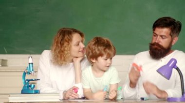 Yaratıcılık setiyle oynayan neşeli bir aile. Ebeveynler, ilk günden önce küçük oğullarını cesaretlendiriyorlar. Mutlu bir aile. İlkokuldan bir çocuk..