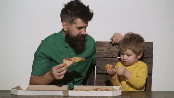 Man eten heerlijke pizza met kind jongen. Schattige kleine Kaukasische jongen eten pizza met bebaarde man geïsoleerd op witte achtergrond. Hongerig kind het nemen van een hapje van pizza. Pizza levering. Familie lunch. — Stockvideo