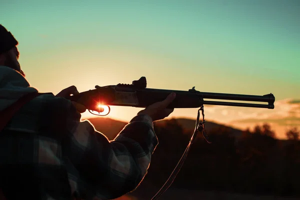 Hunter man. Vat van een pistool. Geweer jager Silhouetted in een prachtige zonsondergang. Jager met krachtig geweer met Scope spotting dieren. Ruimte kopiëren voor tekst. — Stockfoto