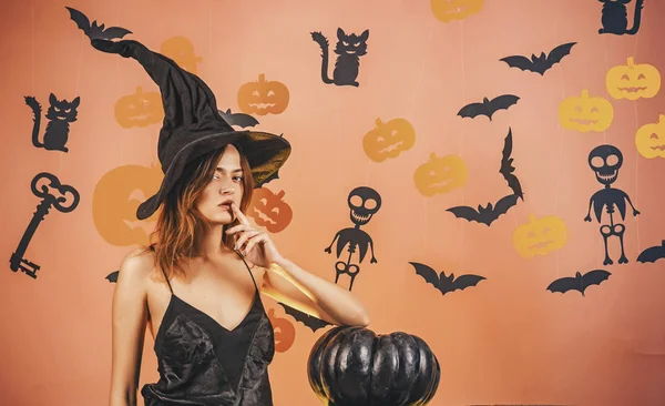 Halloween vrouw ontwerp. Halloween heks met een gebeeldhouwde pompoen en magische lichten. Sexy modellen poseren op Halloween achtergrond. — Stockfoto