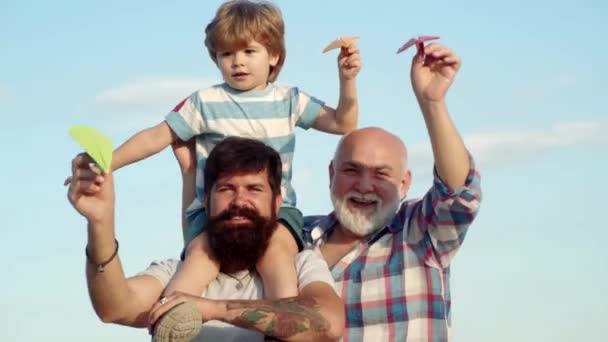 Retrato de un padre feliz dando a su hijo paseo a cuestas sobre sus hombros y mirando hacia arriba. Concepto de infancia. Vacaciones familiares y unión. Padre hijo y abuelo relajándose juntos . — Vídeo de stock