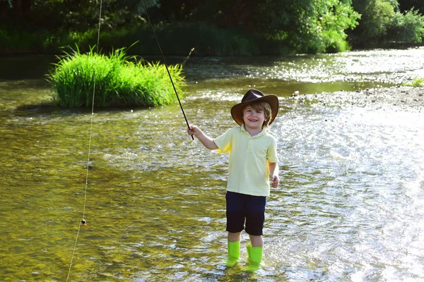 Nehirde küçük çocuk balık tutuyor. Nehir kıyısında olta yla sarı gömlekli çocuk. Güzel nehirde olta kullanan balıkçı çocuk. — Stok fotoğraf
