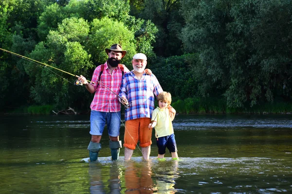 Ritratto di figlio, padre e nonno felice - tre generazioni di uomini che pescano sul fiume. Nonno e padre con bambino carino ragazzo stanno pescando . — Foto Stock
