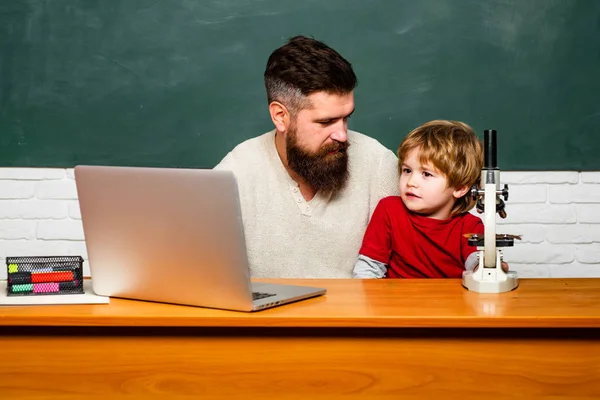 Child learning. Daddy and son together. Teacher and schoolboy using laptop in class. Back to school and Education concept. Young or adult. Elementary school kid and teacher in classroom at school. — Stock Photo, Image