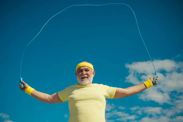 Portrait of old man exercising with jumping rope on blue sky background. Freedom retirement concept. Portrait of healthy senior sport man. Be in motion. Sporting. — Stock Photo, Image