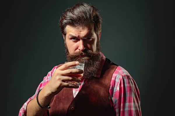Selbstbewusster, gut gekleideter Mann mit einem Glas Whisky. Mann mit Bart hält Glasbrand in der Hand. Barmann oder Barkeeper serviert Cognac. — Stockfoto