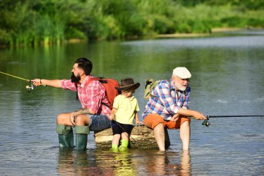 Baba oğluna nehirde balık avlamayı öğretiyor. Anglers. Yaz aylarında nehirde balık avlamak için 3 adam. Baba, oğul ve büyükbaba balık avına çıktı.