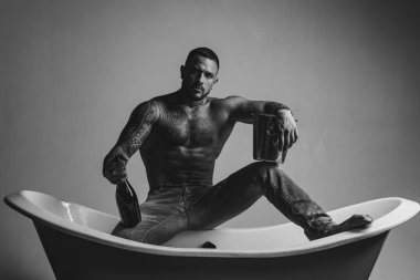 Lüks elit eğlence. Elinde bir şişe şampanya olan çekici bir adam. Alkollü vahşi adamlar. Siyah beyaz fotoğraf.