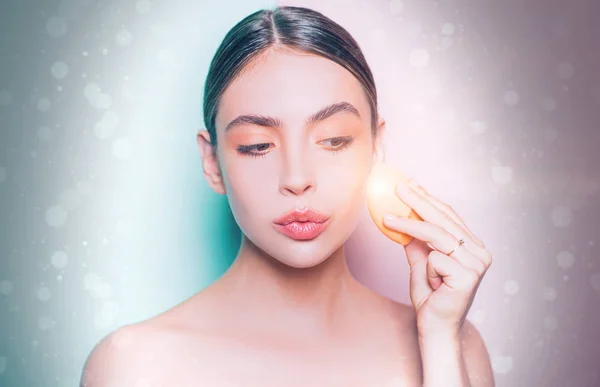 Tom de pele perfeito. Aplicar corretor e iluminador cosmético. Menina segurar aplicador cosmético. Uma mulher a espalhar creme na cara. Conceito de creme de pele. Cuidados faciais para a mulher. Conceito de pele fresca e saudável — Fotografia de Stock