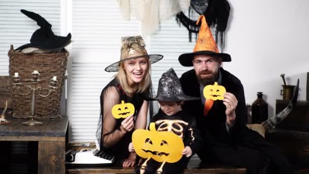 A família feliz em trajes mantém abóboras de papel na celebração da Véspera de Todos os Santos. Família se diverte no tempo de Halloween. Família feliz. Festa de Halloween e abóbora engraçada. Família sorridente na festa de Halloween . — Vídeo de Stock