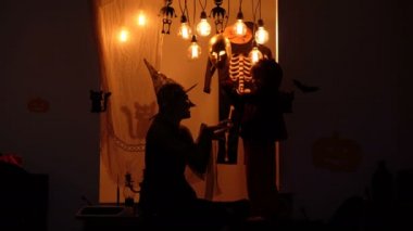 Cadılar Bayramı parti arka plan. Anne ve oğlu eğlenmek ve Cadılar Bayramı'nda oynamak. Ürkütücü cadılar bayramı manzarası. Cadılar Bayramı büyüsü. Cadı uçar ve küçük bir ejderha geri taşır. Cadı ve ejderha siluetleri.