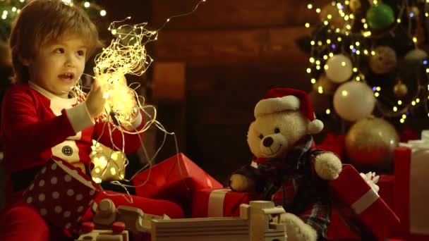 Niños de Navidad. Niño con un regalo de Navidad sobre fondo de casa de madera. Feliz Navidad y Feliz Año Nuevo . — Vídeos de Stock