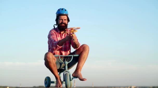 Бородатый смешной человек весело кататься на детском велосипеде на фоне неба. Смешной бородатый мужчина едет на детском велосипеде. Смешной человек веселится на детском велосипеде . — стоковое видео
