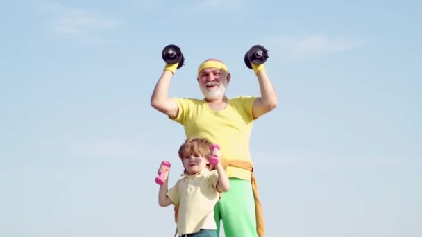 Familia activa disfrutar del deporte y la aptitud. Divertido anciano y niño con mancuernas. Abuelo e hijo hacen ejercicio matutino . — Vídeos de Stock