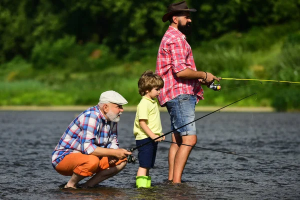 Ritratto di figlio, padre e nonno felice - tre generazioni di uomini che pescano sul fiume. Pescatori familiari che pescano con mulinello . — Foto Stock