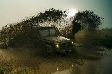 Off-road 4x4 konsepti. Offroad vagonu kötü yolda. Off-road yarışında su sıçraması. Tekerlekleri ve toza dönüşen off-road 'u hareket ettir..