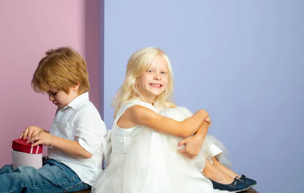 Derreter o coração dela com um presente. Amizade e amor. Lindos meninos ternos. Pequenas crianças amizade. Amizade sincera. Casal adorável crianças roupas brancas. Feliz infância. Menino e menina amigos bonitos — Fotografia de Stock