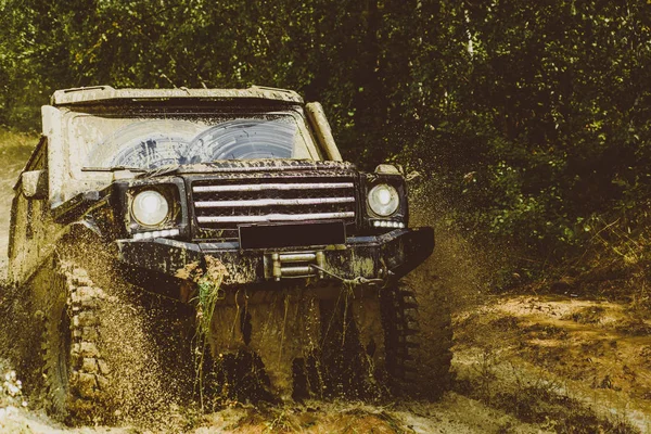 Spostare le ruote pneumatici e fuoristrada che va nella polvere. Veicolo fuoristrada che esce da un buco di fango pericoloso. Il fuoristrada va in montagna. Rally di corsa . — Foto Stock