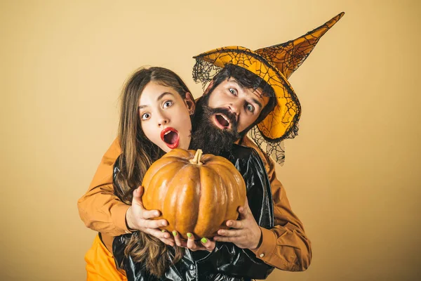 Una coppia di Halloween che abbraccia. I migliori amici hanno festeggiato Halloween. Halloween sorpreso donna e bell'uomo barbuto in cappello di Halloween e costume tenendo zucca. — Foto Stock