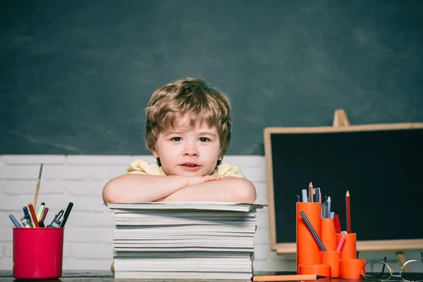 Educación en el hogar o la escuela. Niño retrato de la escuela primaria. Un chico con un libro. Espacio de copia pizarra. Niño lindo en el aula cerca del escritorio de pizarra. — Foto de Stock