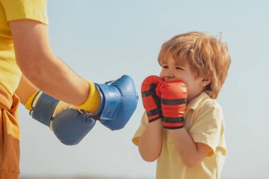 Boksör dedesi ve mavi gökyüzü arka plan üzerinde mavi boks eldivenile çocuk - izole. Büyükbaba ve torunu sabah boks eğitimi yapıyor.