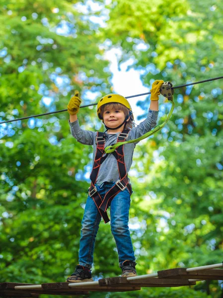 Early childhood development. Eco Resort Activities. Playground. Kids boy adventure and travel. Little child climbing in adventure activity park with helmet and safety equipment. — Stock Photo, Image