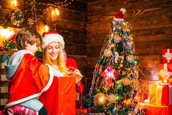 Užijte si každou chvíli. Útulný večer doma. Rodina se baví doma. Šťastná rodina. Rodinné svátky. Máma a dítě spolu zdobí vánoční stromek. Matka a syn přátelský zábava — Stock fotografie