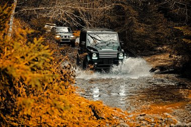 Jeep bir su birikintisine çarptı ve bir toprak spreyi aldı. Off-road yarışlarında çamur ve su sıçraması. Dağ yolunda yoldan çıkar. Çamurda izin iler. 4x4 Off-road suv araba. Offroad arabası. Safari.