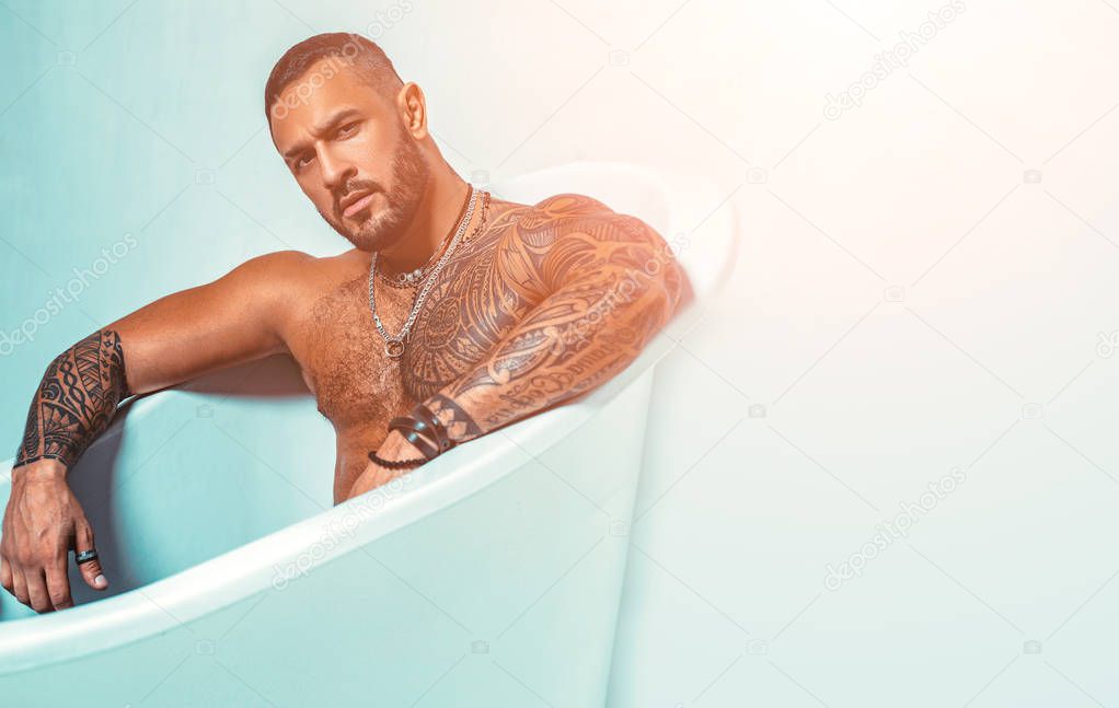 Confidence man. steroids. muscular man with athletic body. sexy abs of tattoo man in bath tub. stay clean and fresh. copy space