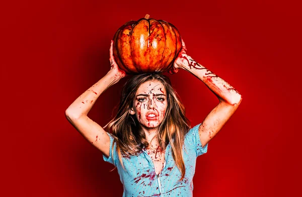 Halloween dziewczyna z dyni. Portret kobiety z makijażu krwi na twarzy. Seksowna kobieta nosi niebieskie dredy z krwią. Ma dynię trzyma w rękach nad głową. — Zdjęcie stockowe