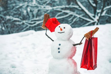 Kış kar arka plan üzerinde hediye ile Kardan Adam. Kardan adam ve kar günü. Hediye bir çanta ile Kardan adam.