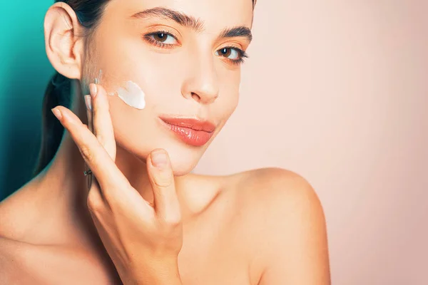 Beautiful woman spreading cream on her face. Skin cream concept. Facial care for female. Keep skin hydrated regularly moisturizing cream. Fresh healthy skin concept. Taking good care of her skin — Stock Photo, Image