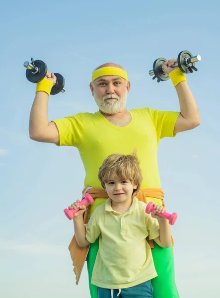 Nonno e bambino in palestra a lavorare con i pesi. Adoro lo sport. Cura del corpo e assistenza sanitaria. Uomo anziano e bambino nel centro benessere familiare . — Foto Stock