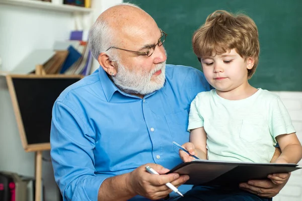 Großvater im Gespräch mit Enkel. Familiengeneration und Beziehungskonzept. glücklicher netter schlauer Junge und alter Lehrer mit Buch. lustiges kleines Kind hat Spaß auf Tafel-Hintergrund. — Stockfoto