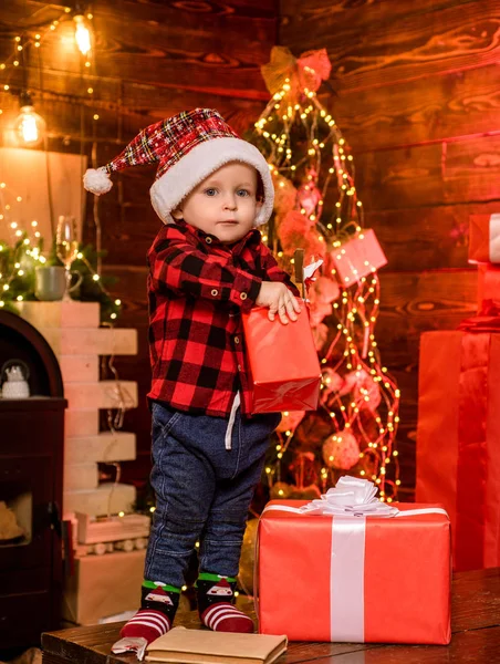 プレゼントを開く。素敵な赤ちゃんはクリスマスをお楽しみください。サンタ少年の小さな子供は、自宅でクリスマスを祝います。子供の頃の思い出男の子かわいい子供陽気な気分クリスマスプレゼント。中に何があるか。陽気で明るいクリスマス — ストック写真