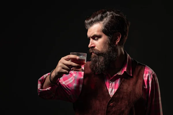 Un hombre seguro y bien vestido con un vaso de whisky. El hombre de negocios se deshace del estrés con whisky. Empresario barbudo en traje elegante con vaso de whisky . — Foto de Stock